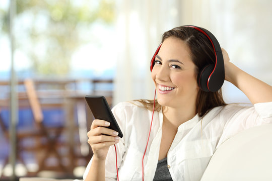 Woman listening to music looking at camera at home