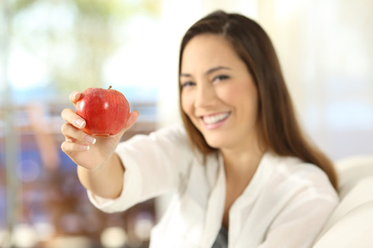 Woman offering an apple and looking at camera