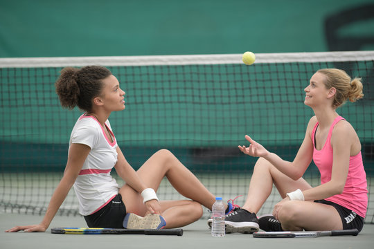 two pretty tennis players sitting on court after match