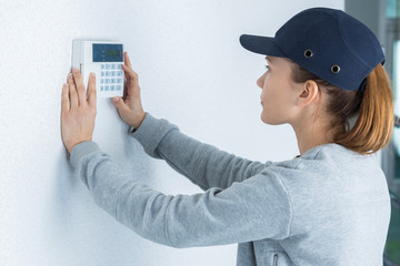 female technician pressing button on digital thermostat