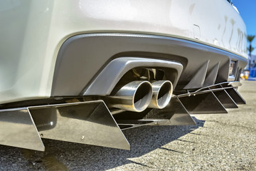 Close up of a dual exhaust pipe on a white car with tail spikes
