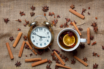 Cup of Christmas tea with alarm clock and ingredients
