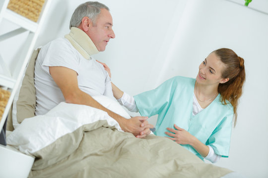 old man in bed with nurse touching his arm