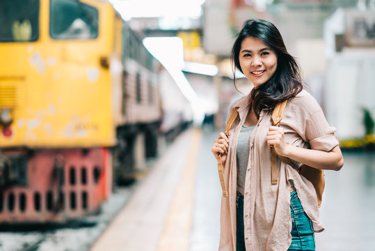 Happy beautiful traveler Asian woman with backpack at train station ready to start her journey.