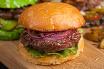 Closeup of set of three mini homemade Burger with marble beef and vegetables on a wooden Board