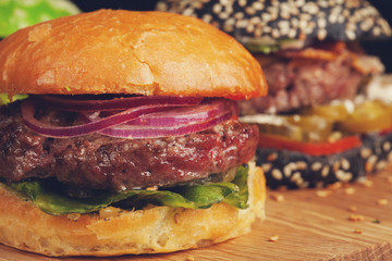 Closeup of set of three mini homemade Burger with marble beef and vegetables on a wooden Board