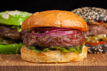 Closeup of set of three mini homemade Burger with marble beef and vegetables on a wooden Board