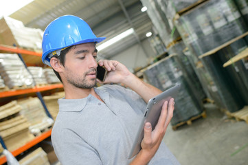 Warehouse worker on phone holding tablet