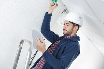 electrician standing on a ladder and using a tablet