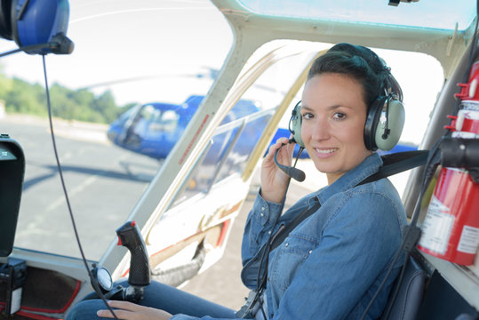 pretty pilot woman in helicopter ready to takeoff