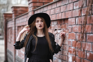Young beautiful girl in a hat and with a dark make-up outside. G