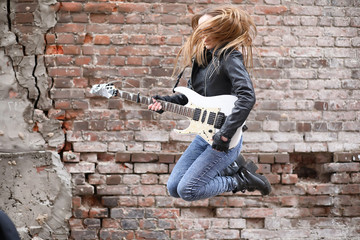  A rock musician girl in a leather jacket with a guitar 