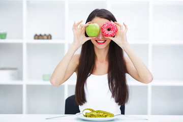 Diet. Woman Measuring Body Weight On Weighing Scale Holding Donut and apple. Sweets Are Unhealthy...