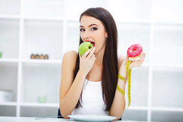 Diet. Woman Measuring Body Weight On Weighing Scale Holding Donut and apple. Sweets Are Unhealthy Junk Food. Dieting, Healthy Eating, Lifestyle. Weight Loss. Obesity.