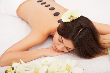 Obraz na płótnie Canvas Spa Stone Massage. Beautiful Woman Getting Spa Hot Stones Massage in Spa Salon. Beauty Treatments Outdoor. Nature