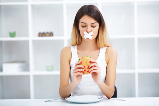 Diet. Young beautiful woman eating burger, It's junk and unhealthy food, Beauty face natural makeup