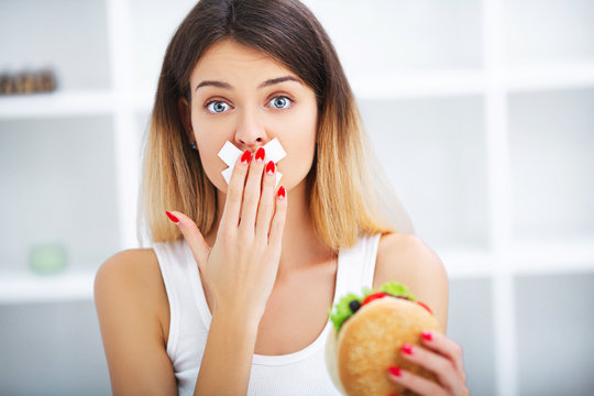 Diet. Young beautiful woman eating burger, It's junk and unhealthy food, Beauty face natural makeup