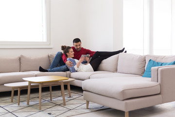 couple relaxing at home with tablet computers