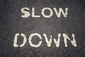 SLOW DOWN print on asphalt road.