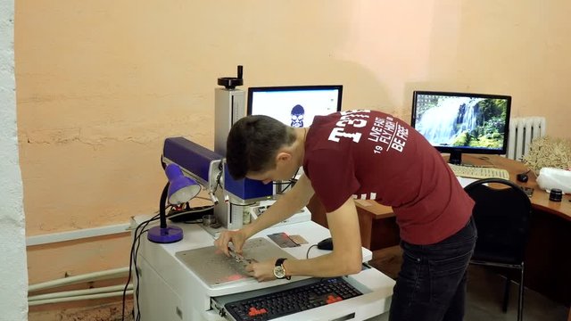 CNC engrave. Laser engraving on metal. Worker monitors the CNC machine.