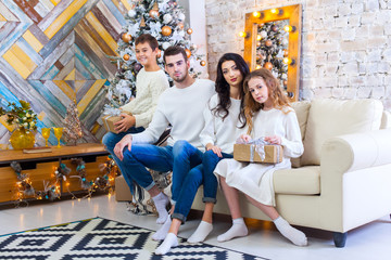 Obraz premium family celebrating at home. father, mother and children on the background of the Christmas tree. New Year and xmas people. Children give fires to parents