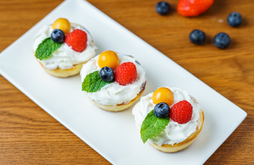 Mini cheesecakes with Strawberry and whipped cream on a plate.
