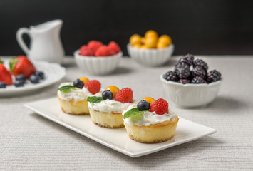 Mini cheesecakes with Strawberry and whipped cream on a plate.