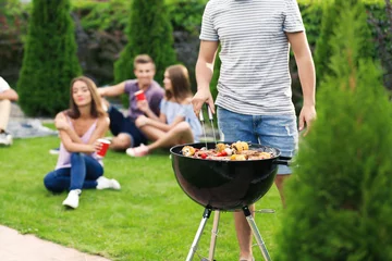Fotobehang Man cooking tasty steaks on barbecue grill for party, outdoors © Africa Studio