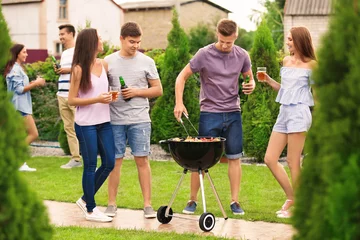  Young friends having barbecue party in garden © Africa Studio