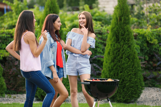 Women cooking tasty food on barbecue grill, outdoors