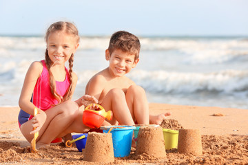 Naklejka premium Cute children playing with sand on sea beach