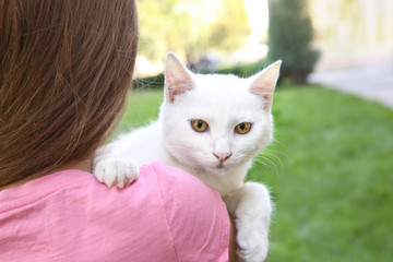 Cute little girl holding white cat outdoors