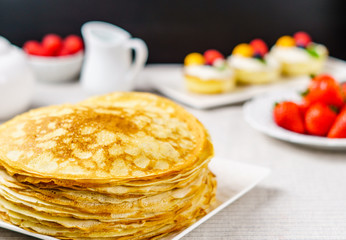 Pile of just made hot Russian pancakes or blini with berries.