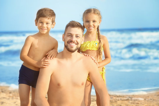Cute little children with father on sea beach at resort