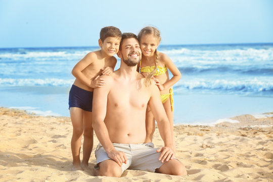 Cute little children with father on sea beach at resort