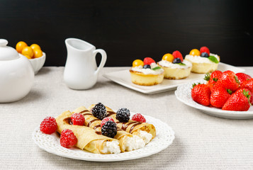 Crepes stuffed with cheese and berry topping on a plate for breakfast.