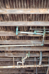 Exposed old plumbing beneath floor boards