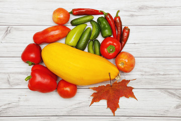Vegetables and autumn leaves on bright wooden table.