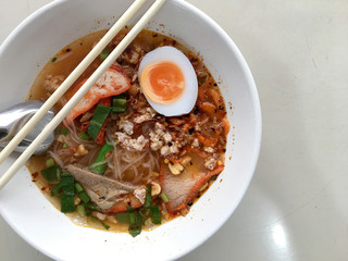Thai style spicy soup and noodle with pork and lemongrass, chilly pasted and lime juice in white blow on table. famous in name Tom Yum.