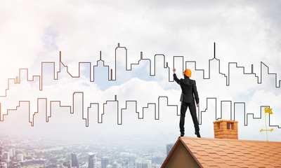 Man architect draw silhouette of modern city on blue sky. Mixed media