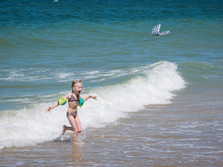 A little girl with a cry flees from the raging ocean.