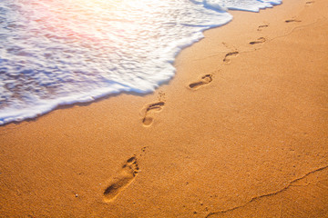 beach, wave and footprints at sunset time