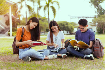 Students young asian together reading book study smiling with tablet,laptop computer at university high school campus,college in summer holiday relaxation