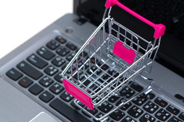Shopping cart or supermarket trolley with laptop notebook isolated on white background, e-commerce and online shopping concept.