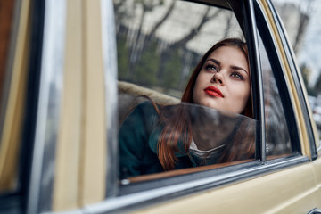 Fototapeta na wymiar Woman with red hair in the car, street, city, red lips