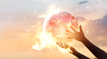 Save the world energy campaign. Planet earth with flame on human hands show energy consumption of...