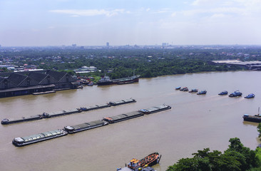 Tugboats towing sand barges along Chao Phraya river , Bangkok , Thailand