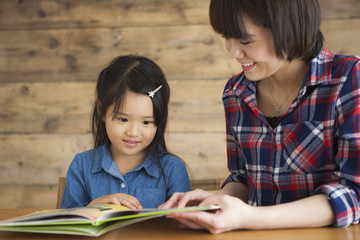 A young mother and a girl read a picture book together.