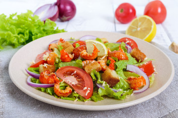 Light tasty salad with meat of a cancer, shrimps, lettuce, garlic croutons, tomatoes, red onions on a white background.