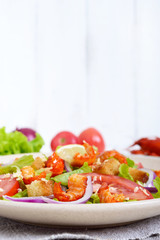Light tasty salad with meat of a cancer, shrimps, lettuce, garlic croutons, tomatoes, red onions on a white background. Free space for an inscription.
